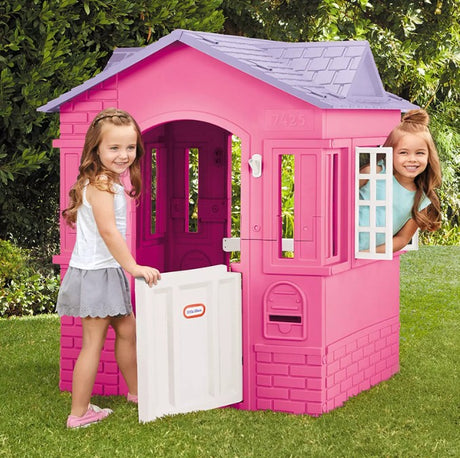 Children playing with Little Tikes Cape Cottage Pink Playhouse in garden - Ireland