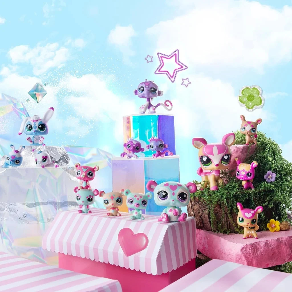 Littlest Pet Shop panda, rabbit, monkey and deer families arranged across pastel pink platforms, clear display blocks and miniature grassy scenery.
