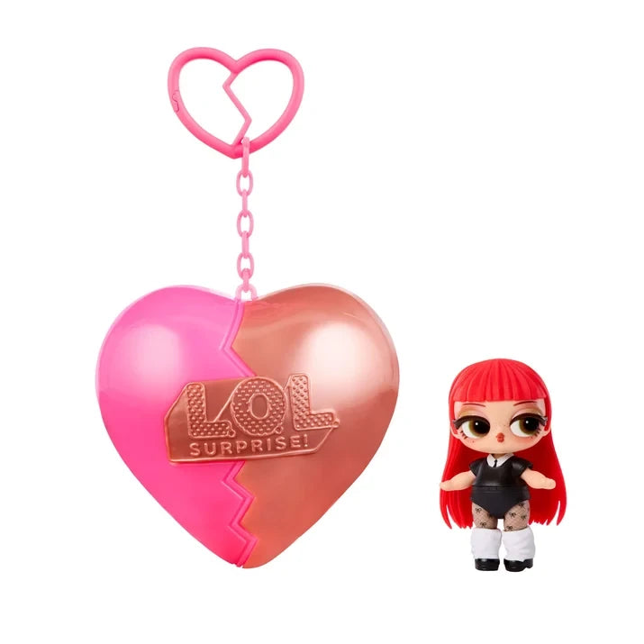 L.O.L. Surprise Music Festival Headliners Tots doll with long straight red hair, a blunt fringe, black outfit, patterned tights and white leg warmers, displayed beside a pink and rose gold heart shaped capsule and keychain.