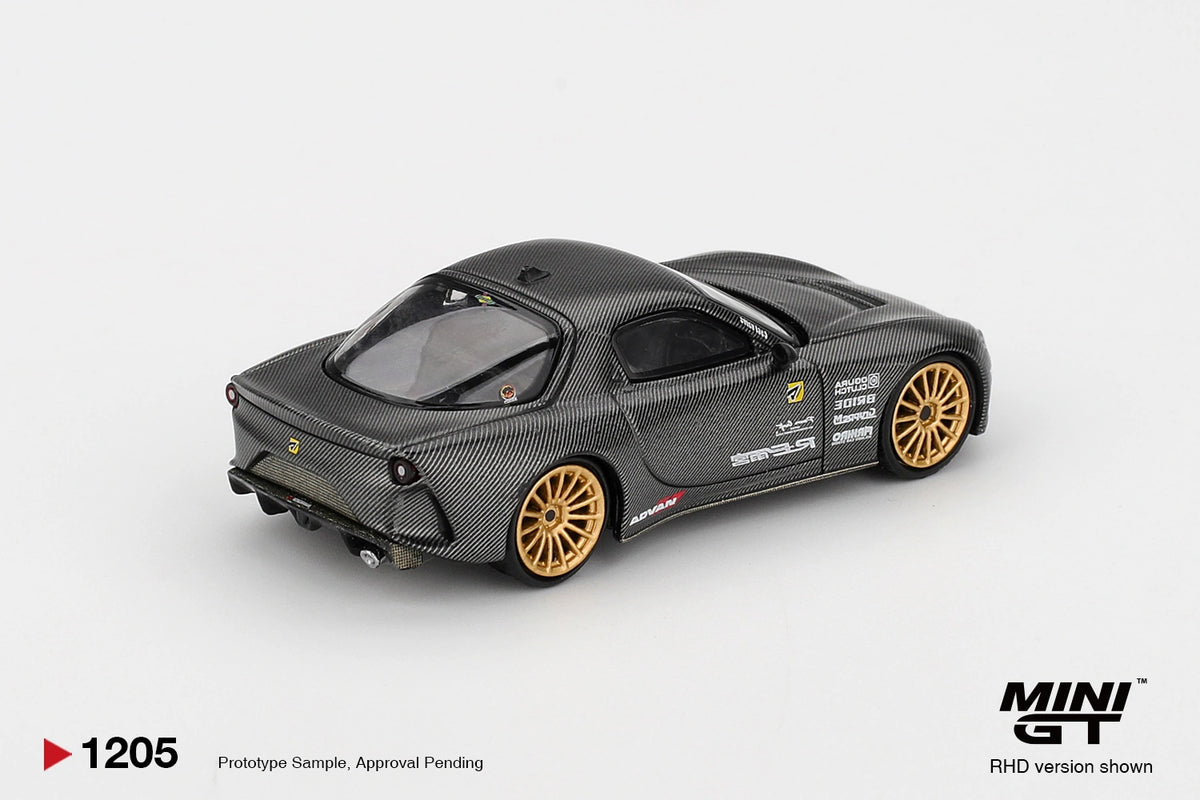 Rear three quarter view of Mini GT Mazda RX-7 RE-Amemiya Matsukiyo KOKU 3 Rotor NA-7 showing carbon effect bodywork, round rear lights, rear spoiler, exhaust and gold racing wheels