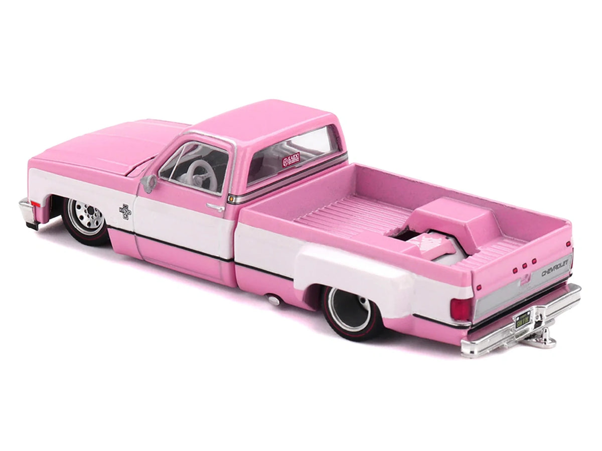 Rear three quarter view of Mini GT Chevrolet Silverado Dually Vintage Spec V2 showing the pink pickup bed, Chevrolet tailgate, chrome rear bumper and wide rear tyres