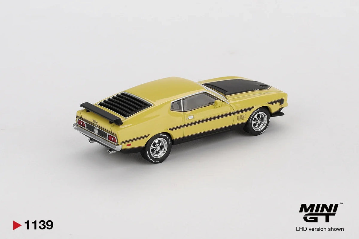 Rear three quarter view of Mini GT Ford Mustang Mach 1 Grabber Yellow LHD showing the black rear window louvres, rear spoiler, chrome bumper, dual exhaust pipes and black side stripes
