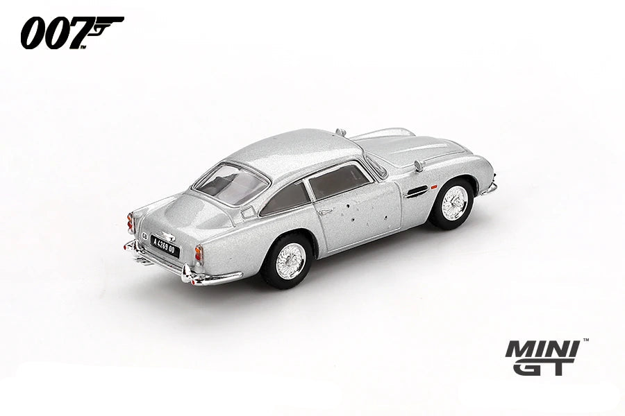 Mini GT James Bond Skyfall Aston Martin DB5 Battle Damaged RHD rear three-quarter view showing bullet marks across the body and rear quarter
