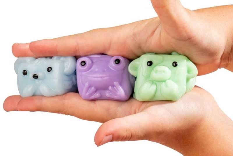 Three MushyKinz Mini Mystery Mushy squishies in blue, purple and green held between two hands