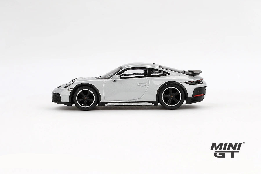 Porsche 911 Dakar Ice Grey Metallic LHD prototype in full side profile showing the black wheel arch trim, raised suspension and rear spoiler