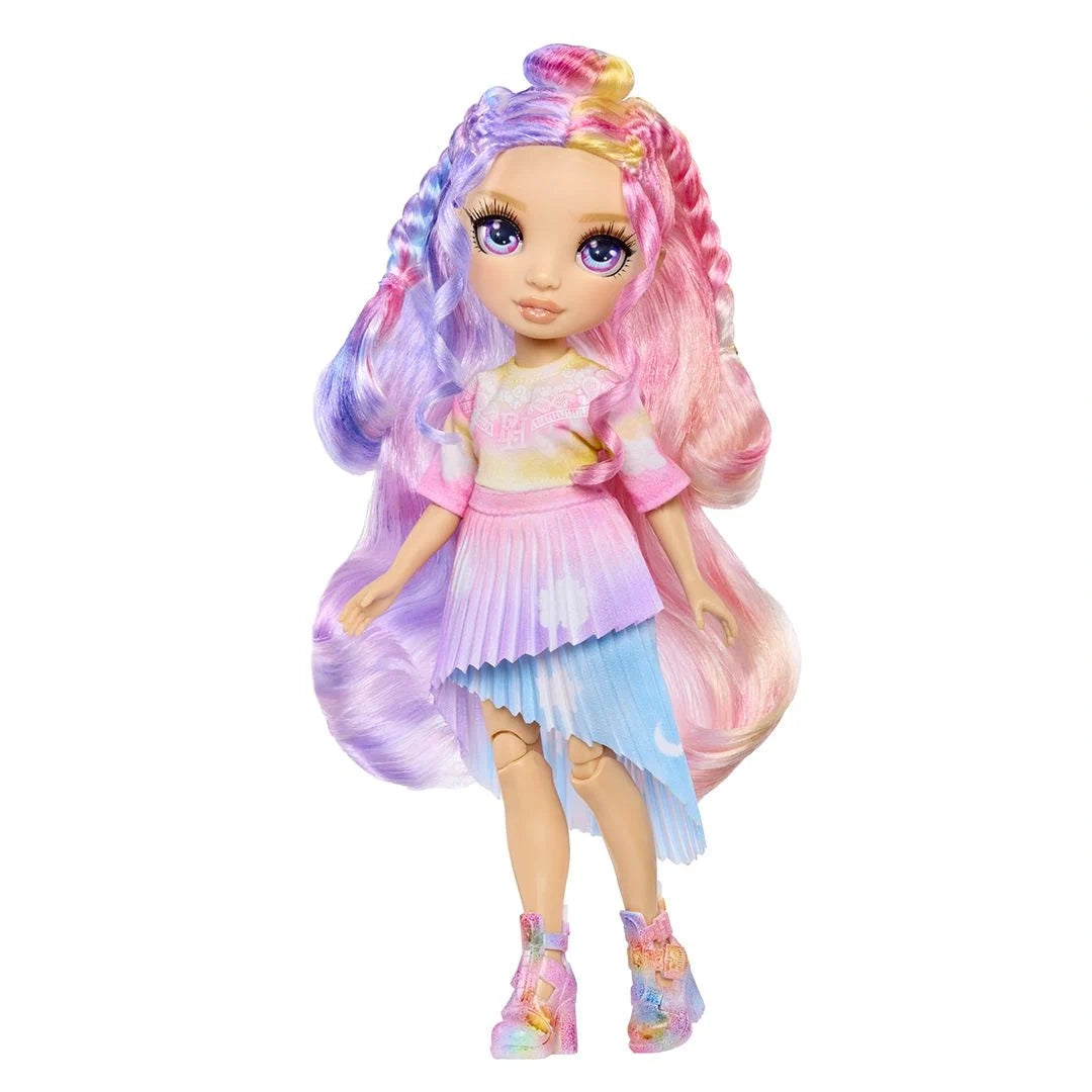 Full length view of the Rainbow High Air Brush & Create doll with long pink, purple and yellow hair, a pastel coloured top, pink and blue pleated skirt and colourful ankle boots against a white background.