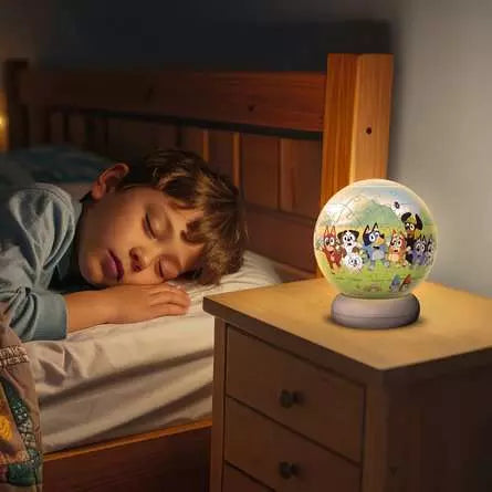 Ravensburger Bluey 3D Puzzle Night Light glowing on a bedside locker beside a sleeping child