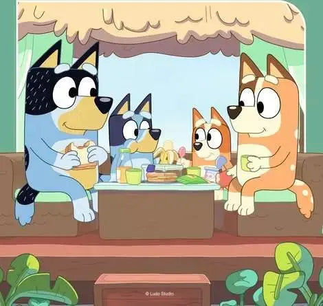 Bluey puzzle artwork showing the Heeler family gathered around a table with food under a thatched shelter, with Bandit, Chilli, Bluey, and Bingo visible