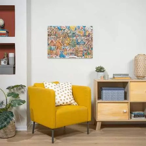 Completed Ravensburger Christmas Cookie Village puzzle displayed on a wall above a yellow armchair