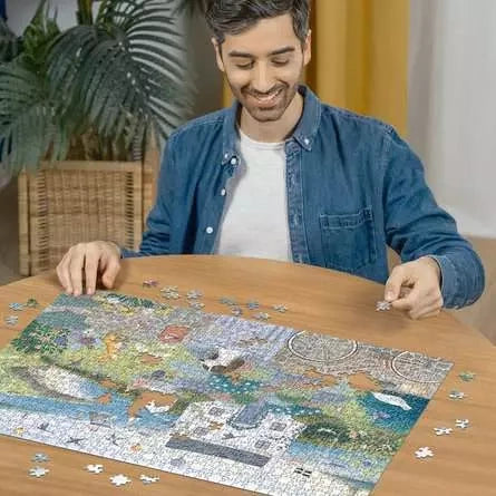Ravensburger Coastal Cottage puzzle being assembled on a table by a man with loose jigsaw pieces around the image