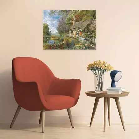 Completed Ravensburger Country Cottage puzzle displayed on a wall above a red armchair and wooden side table