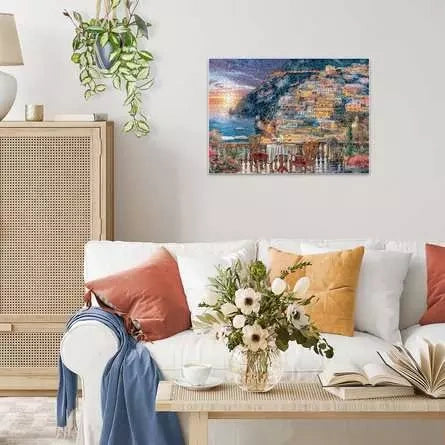 Completed Ravensburger Dinner in Positano puzzle displayed on a living room wall above a white sofa