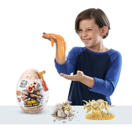 Child holding orange goo above table with Robo Alive Dino Fossil Find egg, broken rock pieces and assembled dinosaur skeleton on white background