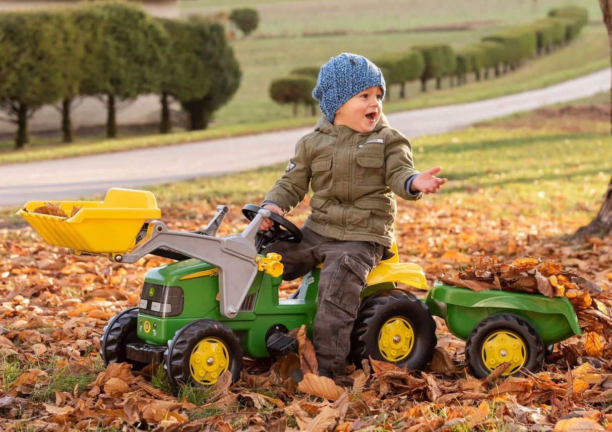Child riding RollyKid John Deere in autumn leaves with front loader raised – Ireland