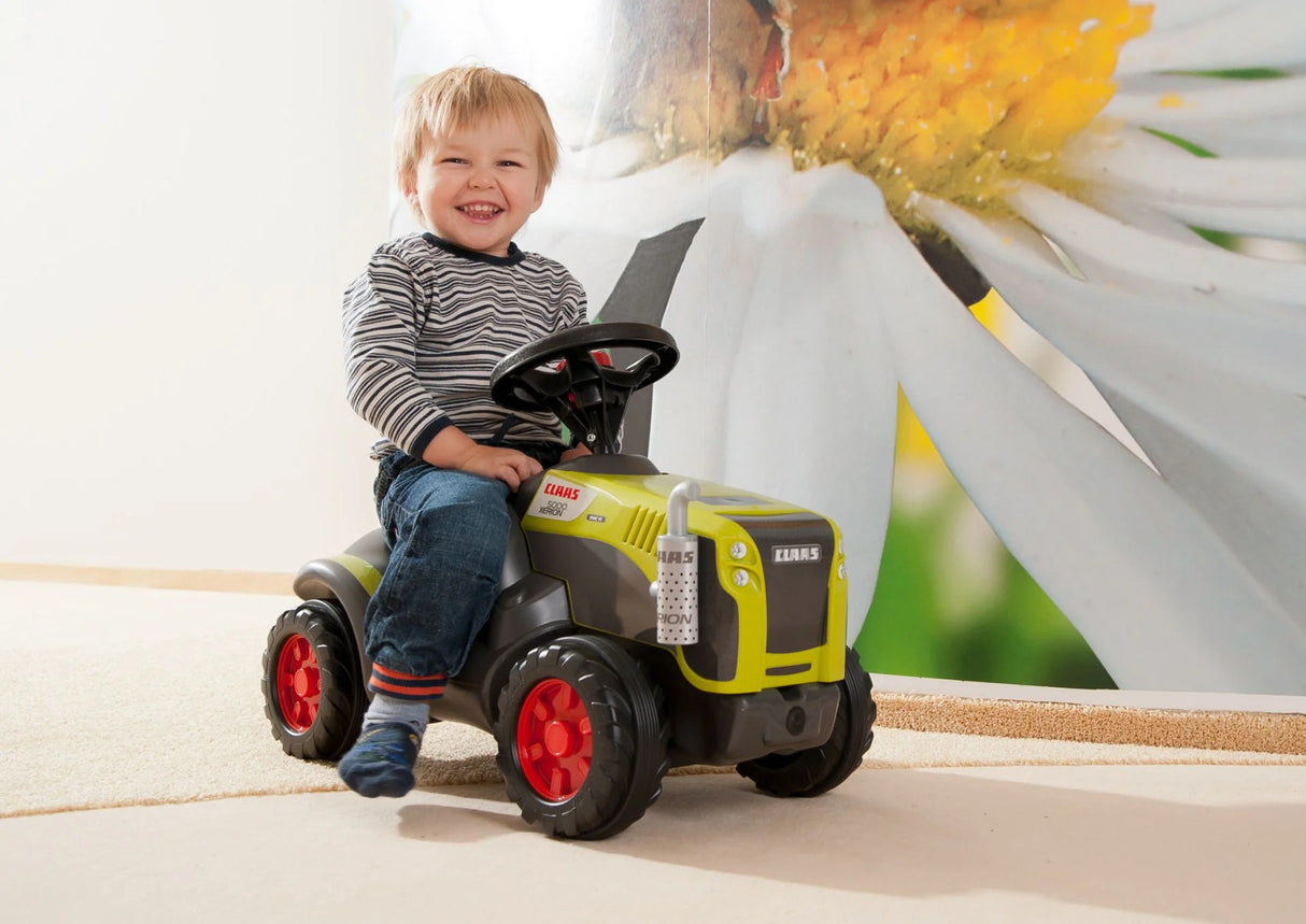 Smiling child on Rolly CLAAS Xerion Minitrac toy tractor indoors – Ireland