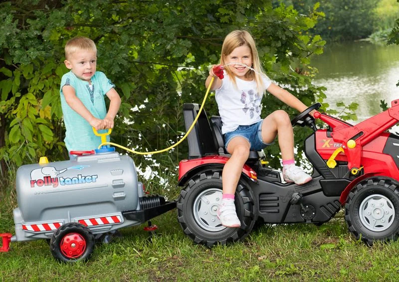 Two children using a Rolly tanker fitted with the blue pump and spraying water safely beside a lake