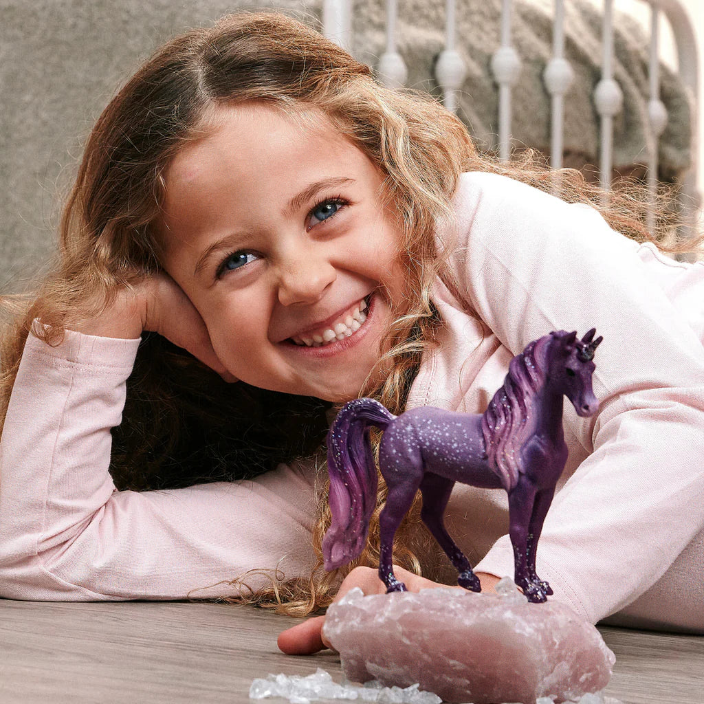 Child playing with the Schleich Galaxy Rainbow Unicorn Mare 70842 purple unicorn figure
