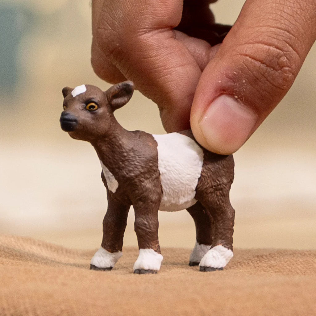 Schleich Goat Kid figure being held upright with brown and white body markings