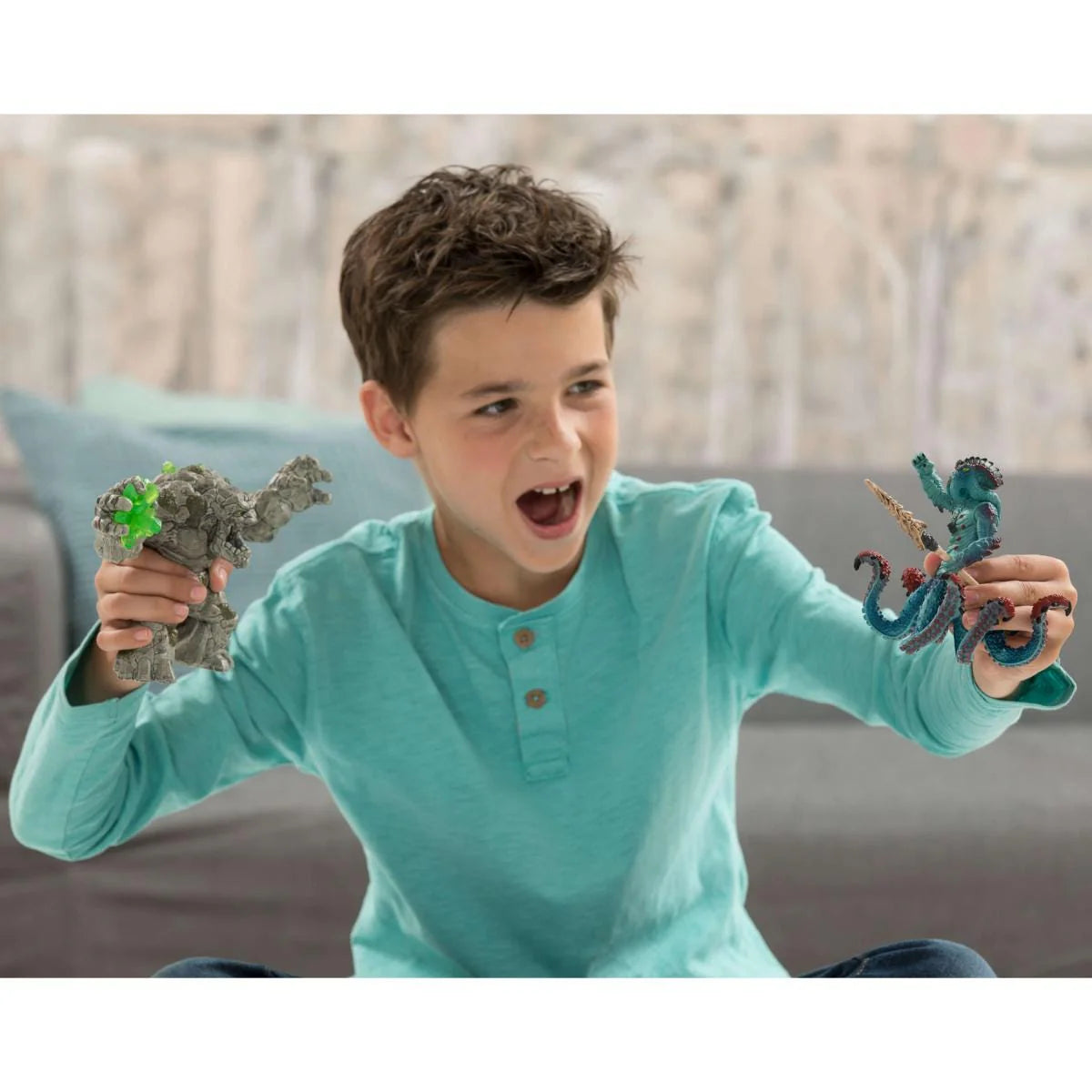 Boy holding a Schleich Stone Monster figure and a blue creature figure