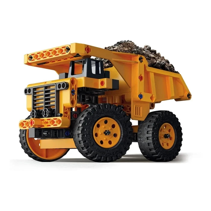 Yellow and black haul truck model with four large wheels and a tipper carrying dark pieces.