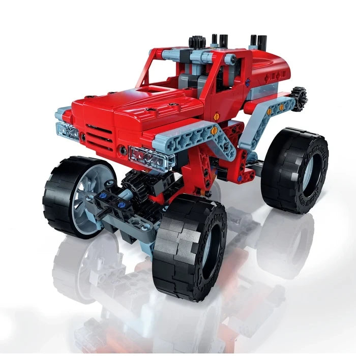 Red monster truck model with four large black wheels, grey frame pieces and a raised cab.