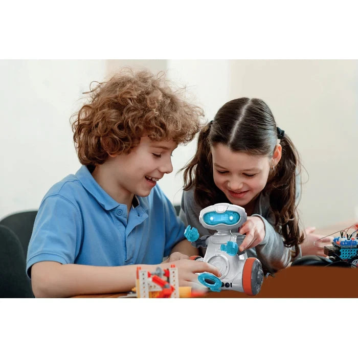 Two children seated at a table using the assembled Mio robot.