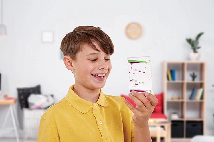 Boy wearing a yellow polo shirt holding a Sensory Motion Bubbler Stair with green and pink droplets