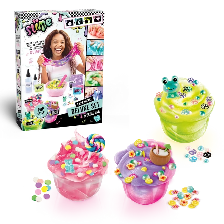 So Slime Experience Deluxe Set Pop Style retail box displayed alongside three finished pink, green and purple slime pots decorated with sweets, a frog charm, paw prints, flowers and a coconut drink.