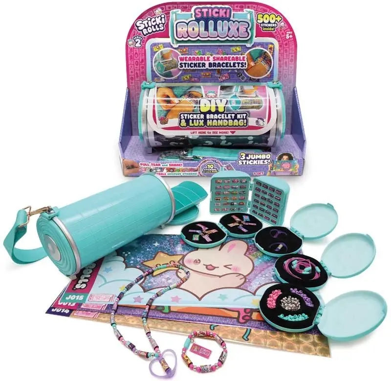 Flat lay of Sticki Rolluxe contents including teal cylinder case, open mini compartments with beads and cords, sticker sheets, and completed bracelet and necklace