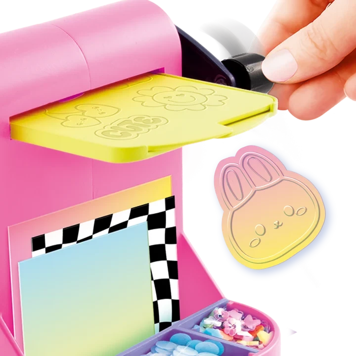 Close-up of the pink Style 4 Ever Scrapbooking Studio Pro embossing machine with a yellow embossing plate and black turning handle, alongside a pastel coloured bunny face decoration with raised details.