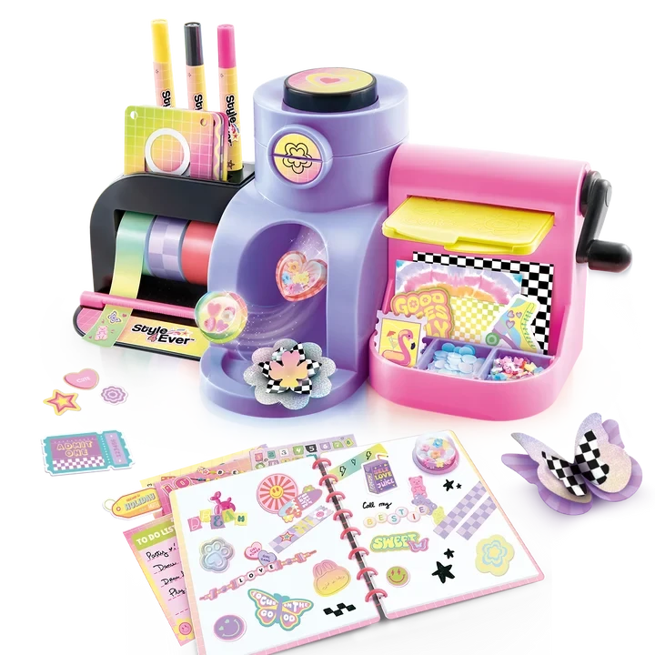 Assembled Style 4 Ever Scrapbooking Studio Pro showing colourful tape rolls, three markers, pink embossing machine, yellow plate and craft storage compartments, with an open decorated scrapbook, raised stickers and paper flower decorations in front.