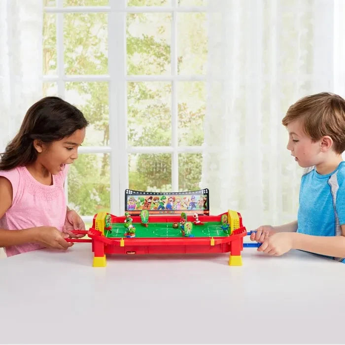 Two children sitting at a table with the Super Mario Football Striker game