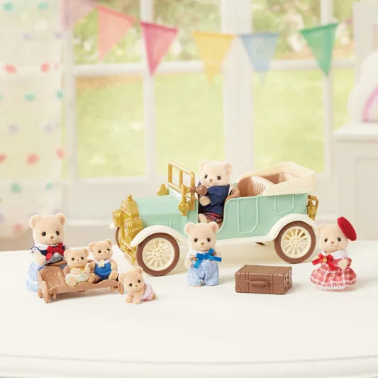 Sylvanian Families animal figures gathered around the mint green Classic Family Car with pram, suitcase and picnic accessories on a tabletop.