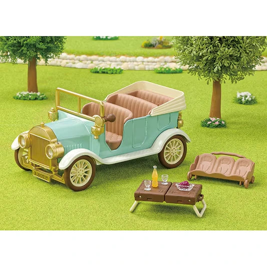 Sylvanian Families Classic Family Car parked in a grassy setting with its brown picnic table, drinks, accessories and removable seat displayed beside it.