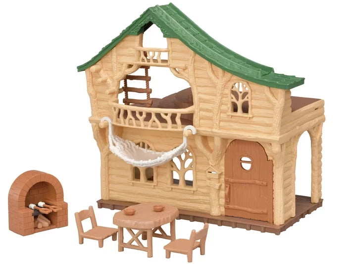 Sylvanian Families Lakeside Lodge log cabin with green roof, hanging white hammock, brick stove, wooden table and two chairs on a white background.
