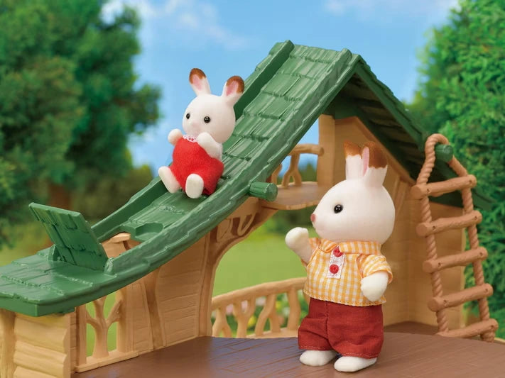 Sylvanian Families rabbit figure sliding down the green roof slide of the Lakeside Lodge, with another rabbit standing beside the rope ladder.