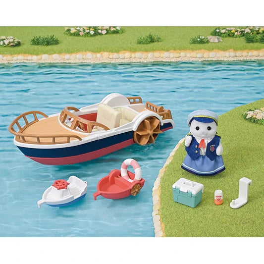 Sylvanian Families leisure boat by a riverbank with seal mother in blue sailor dress, red and white small boats, cool box, drinks bottle and white attachment piece.