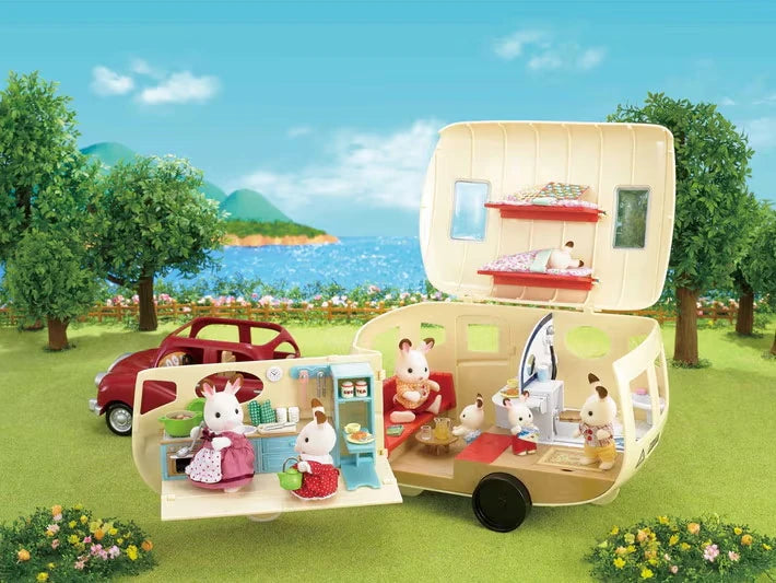 Cream Sylvanian Families caravan opened beside a red car, animal figures, trees and seaside background