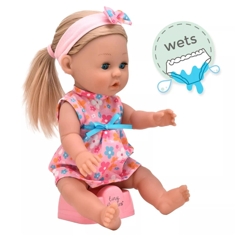 Tiny Tears Classic doll sitting on the pink potty in her floral dress with long blonde hair, with a wetting feature graphic beside her