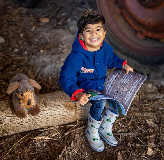 Child in Tractor Ted coat and boots reading Spuds in Mud storybook – Ireland