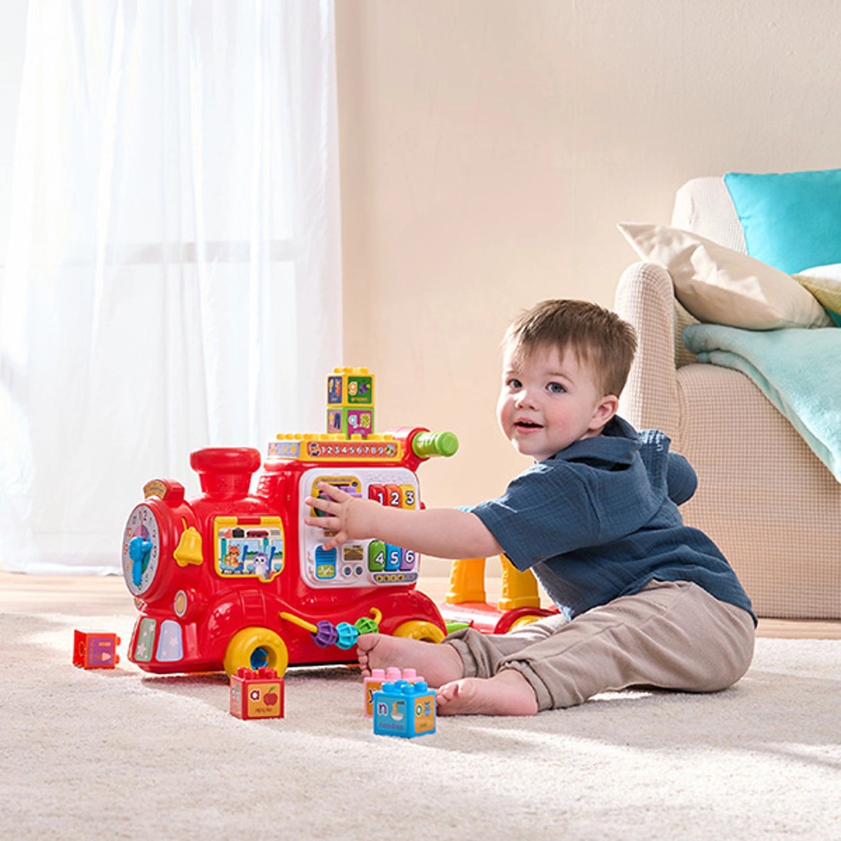 Child seated on the floor playing with the VTech 4-In-1 Alphabet Express and colourful learning blocks
