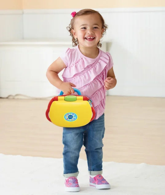 VTech Baby’s Laptop carried by smiling toddler in pink top – Ireland
