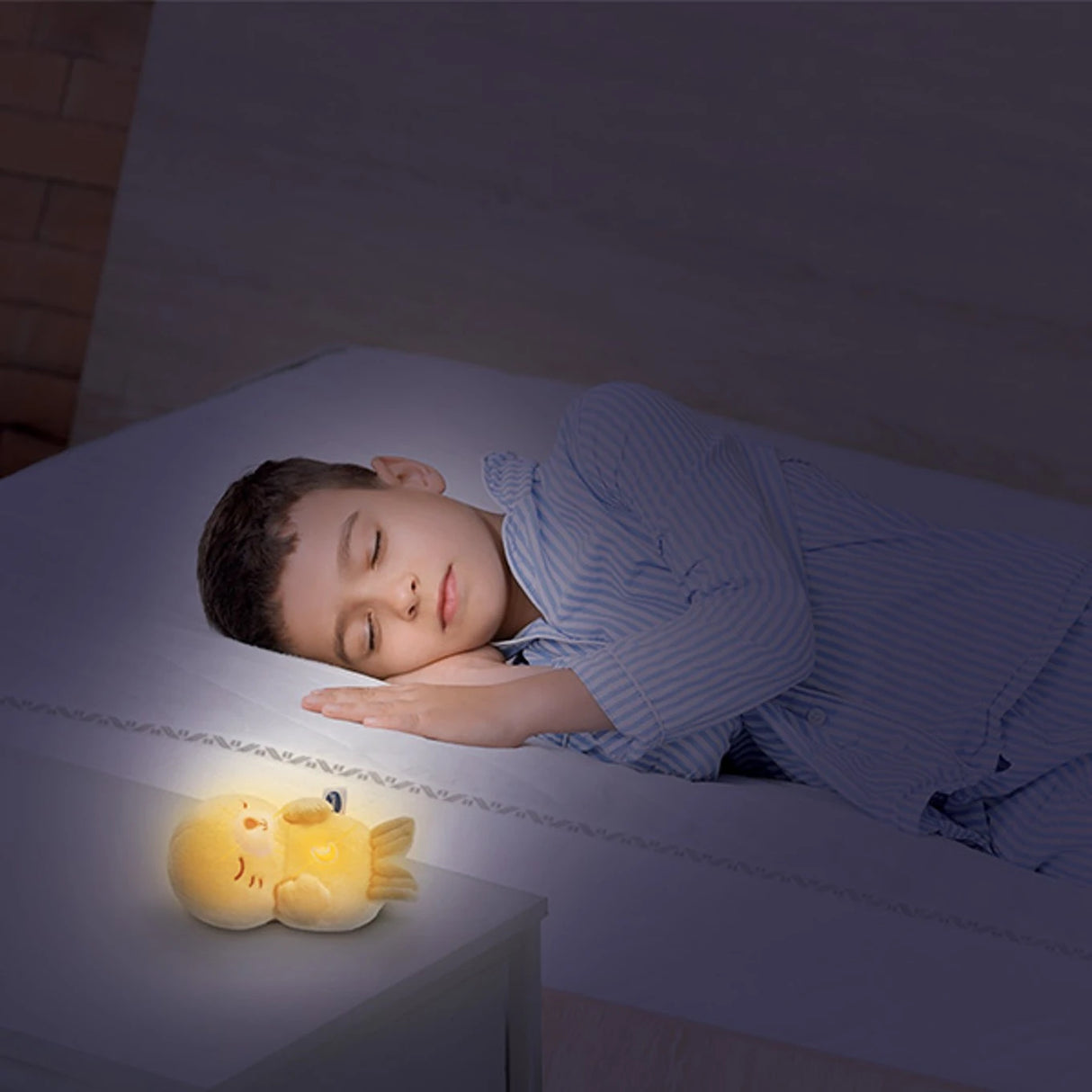 Child in bed beside a glowing VTech Calming Lights Otter on a bedside table
