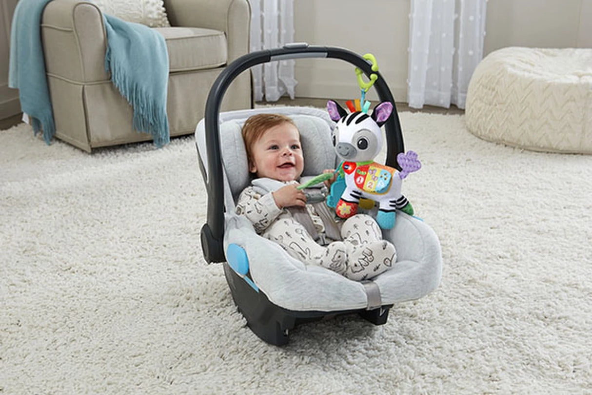 Baby in carrier with VTech On-the-Go Soft Zebra attached to the handle