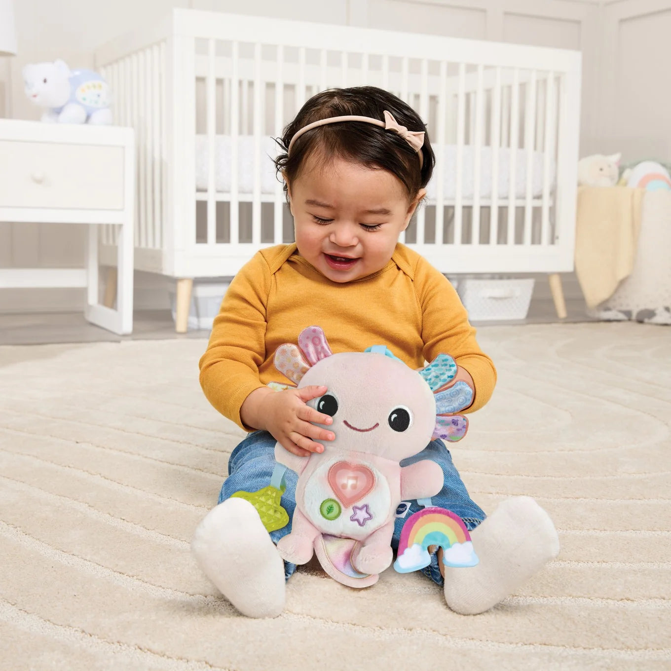Baby playing with soft VTech Rainbow Lights Axolotl on nursery floor – Ireland.