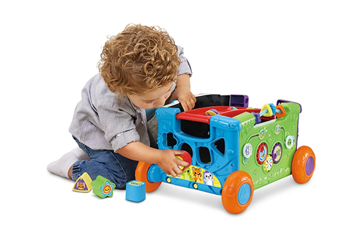 Child placing shape block into VTech Sort & Discover Activity Wagon shape sorter while kneeling on floor