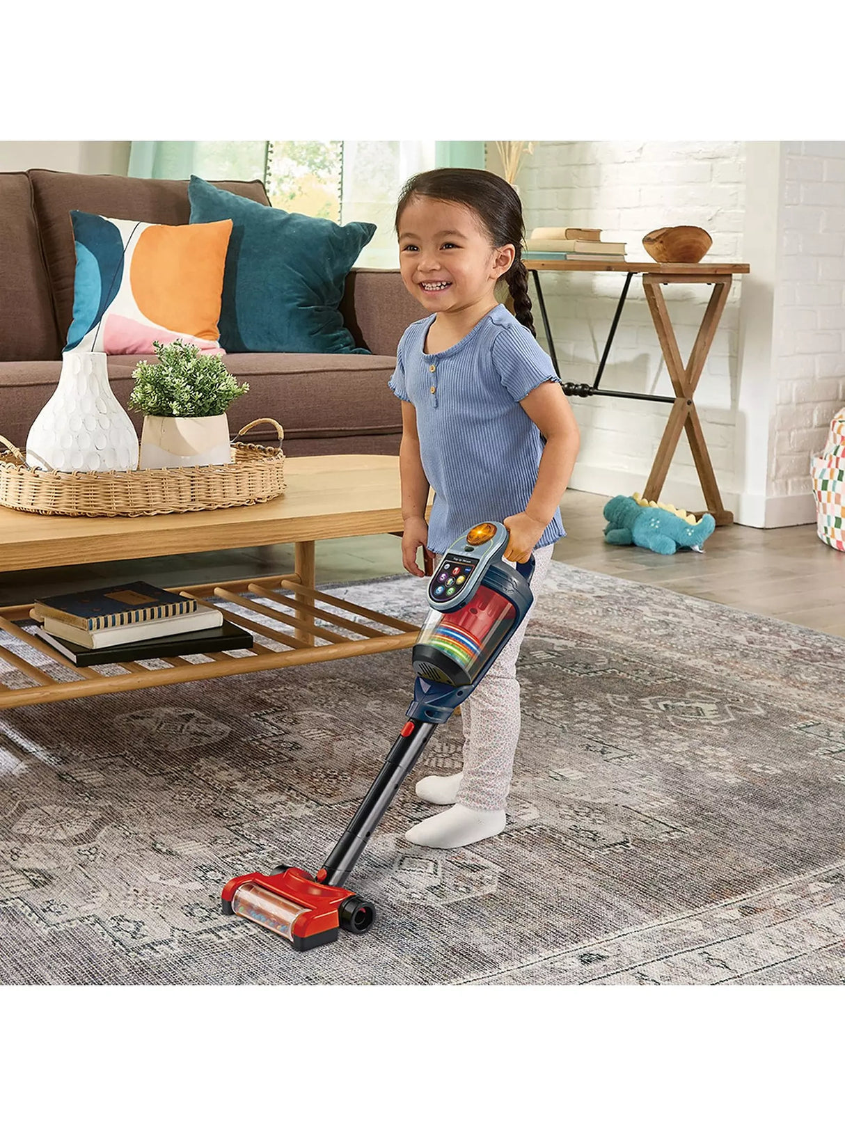 VTech Tidy Up Vacuum with a child using the stick vacuum on a patterned rug in a living room