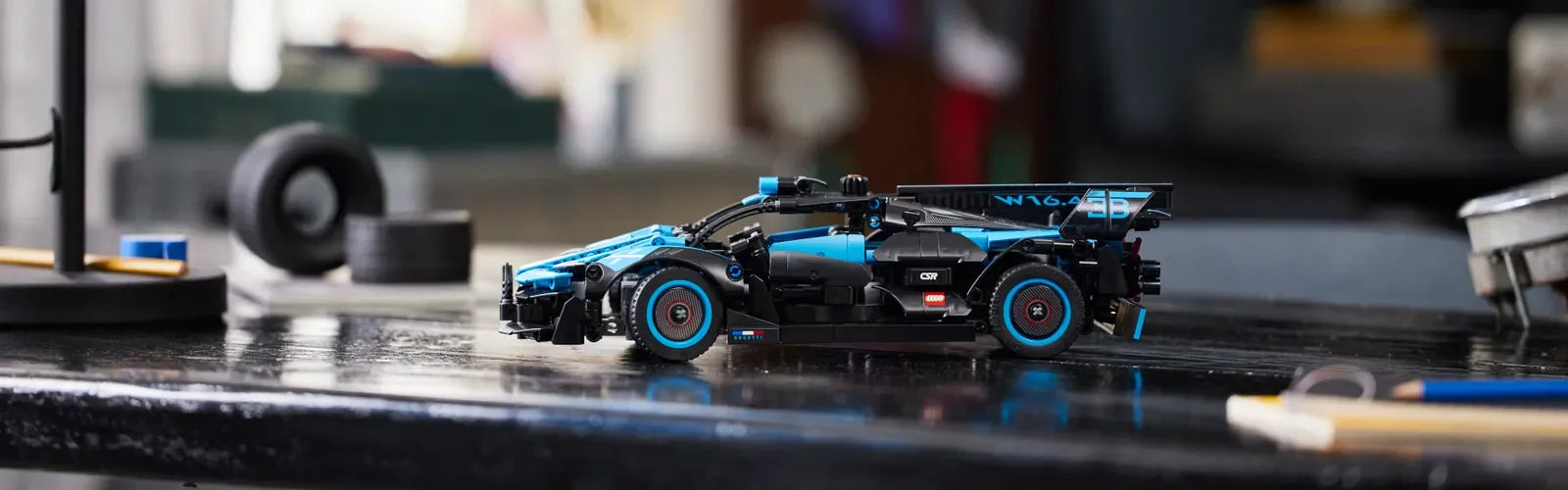 LEGO Technic blue and black race car model displayed on a workshop bench with tools and tyres in Ireland.