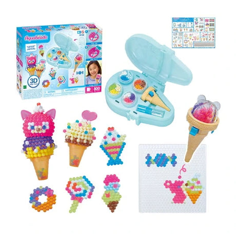 Aquabeads Ice Cream Party Craft Studio retail box displayed with the open turquoise storage case, ice cream bead pen, bead templates and a selection of completed ice cream cones, lollies and sweets.