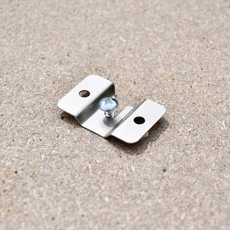 Close-up of the silver metal dartboard mounting bracket with two fixing holes and a central screw on a wooden surface.